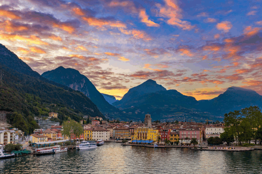 Vista del Lago di Garda e di Riva del Garda al tramonto con le montagne che fanno da sfondo a un paesaggio mozzafiato. 