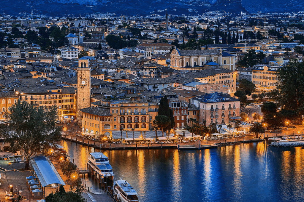 Vista di Riva del Garda che affaccia sul Lago di Garda in un contesto tipicamente notturno con le luci del suo centro città.