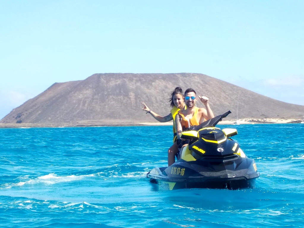 Coppia su moto d'acqua con una montagna di Fuerteventura sullo sfondo