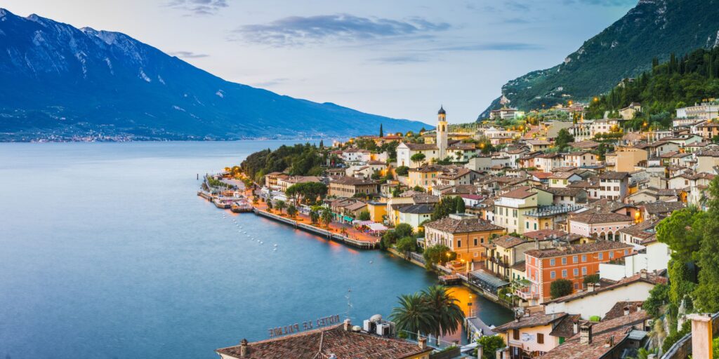 Immagine che rappresenta in lontananza uno dei tipici borghi del Lago di Garda che affaccia sul lago stesso.